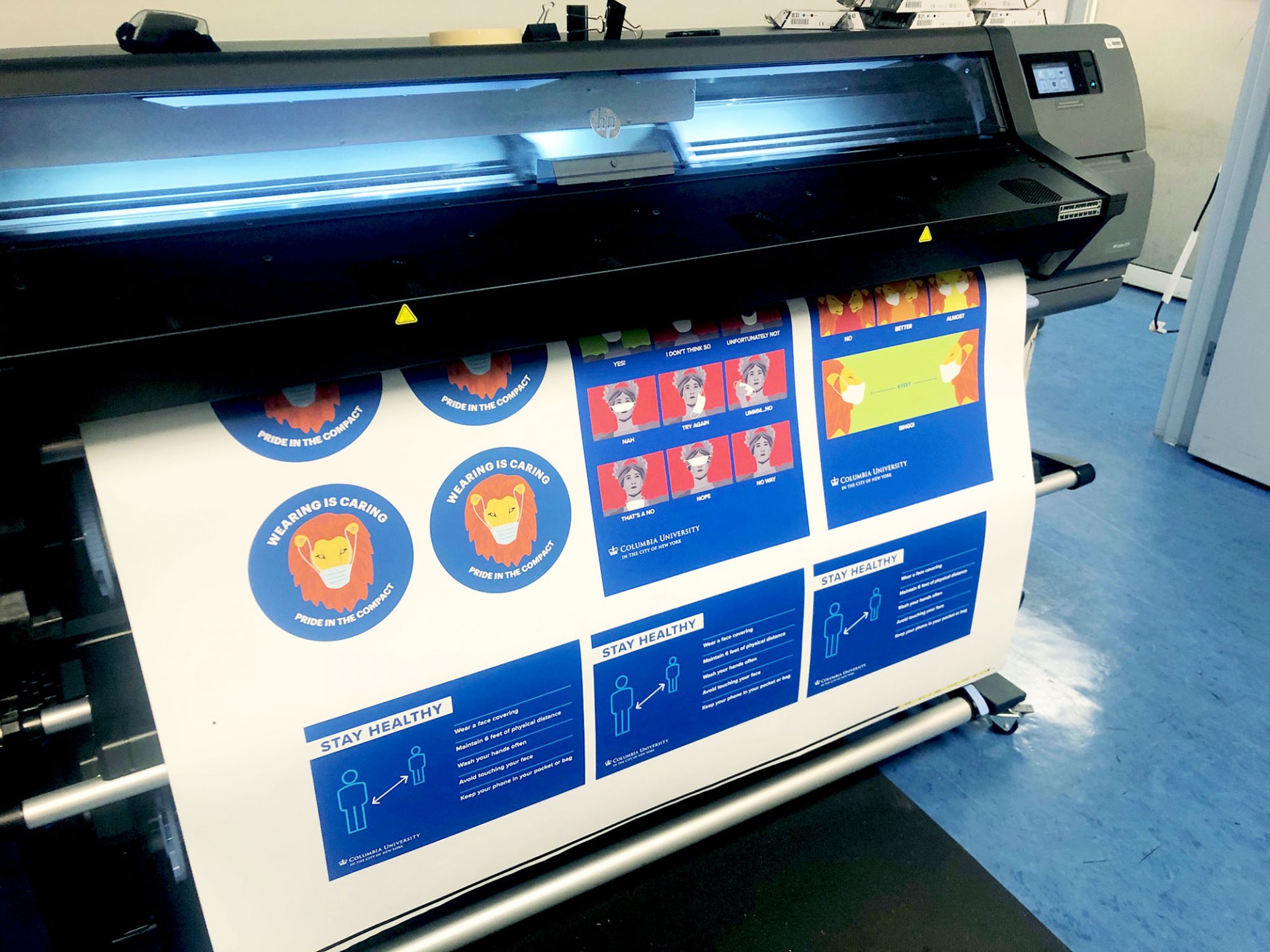 Printer printing a sample sheet of all the types of postcards and stickers Columbia Print created for the Stay Healthy campaign