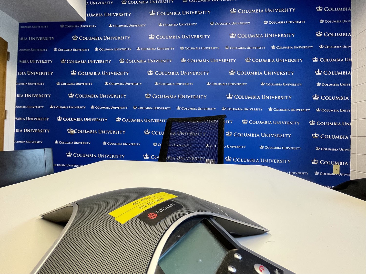 Event Management conference room with the new wall graphic displayed. The wall is a royal blue color with the Columbia University logo repeated in white across the entire space.