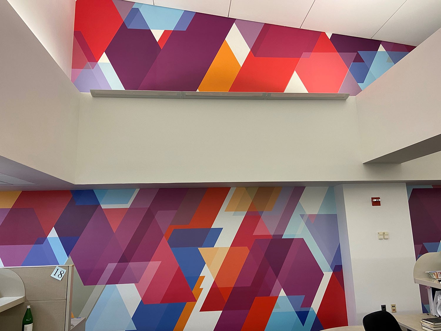 "After" photo of the ISERP space. The formerly-white ceiling and walls are now covered in the colorful, zig-zag pattern of the custom wall graphic, making the space look more vibrant, finished, and welcoming.